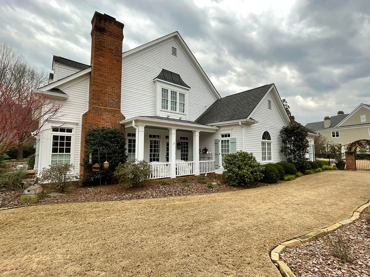 White home in Roswell with covered porch, large windows and brick chimney